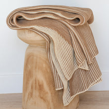 Load image into Gallery viewer, Folded ribbed knit cotton throw blanket in cacao brown and oat milk tones displayed on a carved wooden stool