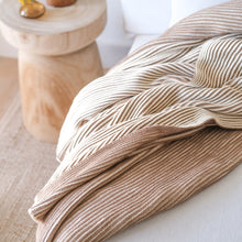 Load image into Gallery viewer, Close-up of ribbed cotton knit throw blanket in cacao and oat milk tones draped on a neutral sofa with soft natural lighting