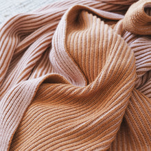 Load image into Gallery viewer, Close-up of ribbed knit cotton throw blanket in warm burnt orange and pink clay tones, softly draped to show texture and stitching detail