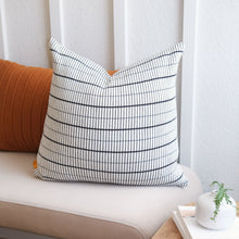 Load image into Gallery viewer, Small grid pillow cover styled on neutral chair with rust accent pillow and white vase for modern living room look
