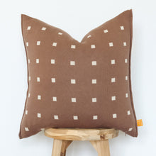 Load image into Gallery viewer, Mocha brown pillow cover with geometric checkers, placed on a stool.
