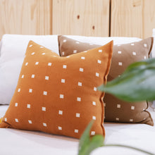 Load image into Gallery viewer, Burnt orange and cacao brown geometric pillow styled on a sofa with plants nearby.
