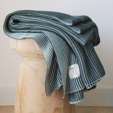 Load image into Gallery viewer, Folded ribbed cotton knit throw blanket in mint blue and dark green on a carved wooden stool with Lumi Living tag visible
